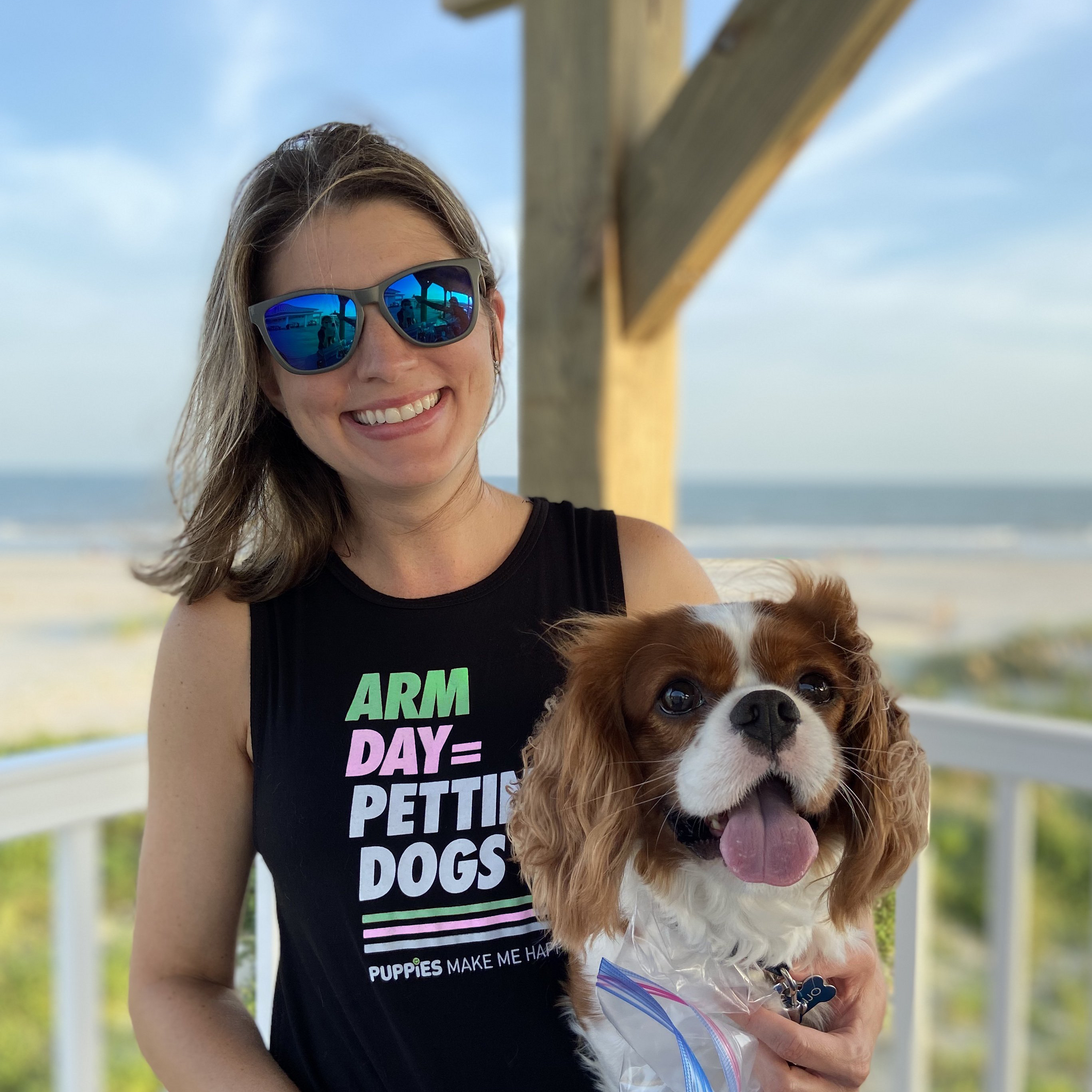 WOMEN WEARING A BLACK SLEEVELESS TANK WITH ARM DAY PETTING MORE DOGS WHILE HOLDING A DOG